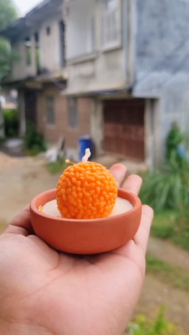 Orange sculpted candle in a clay diya